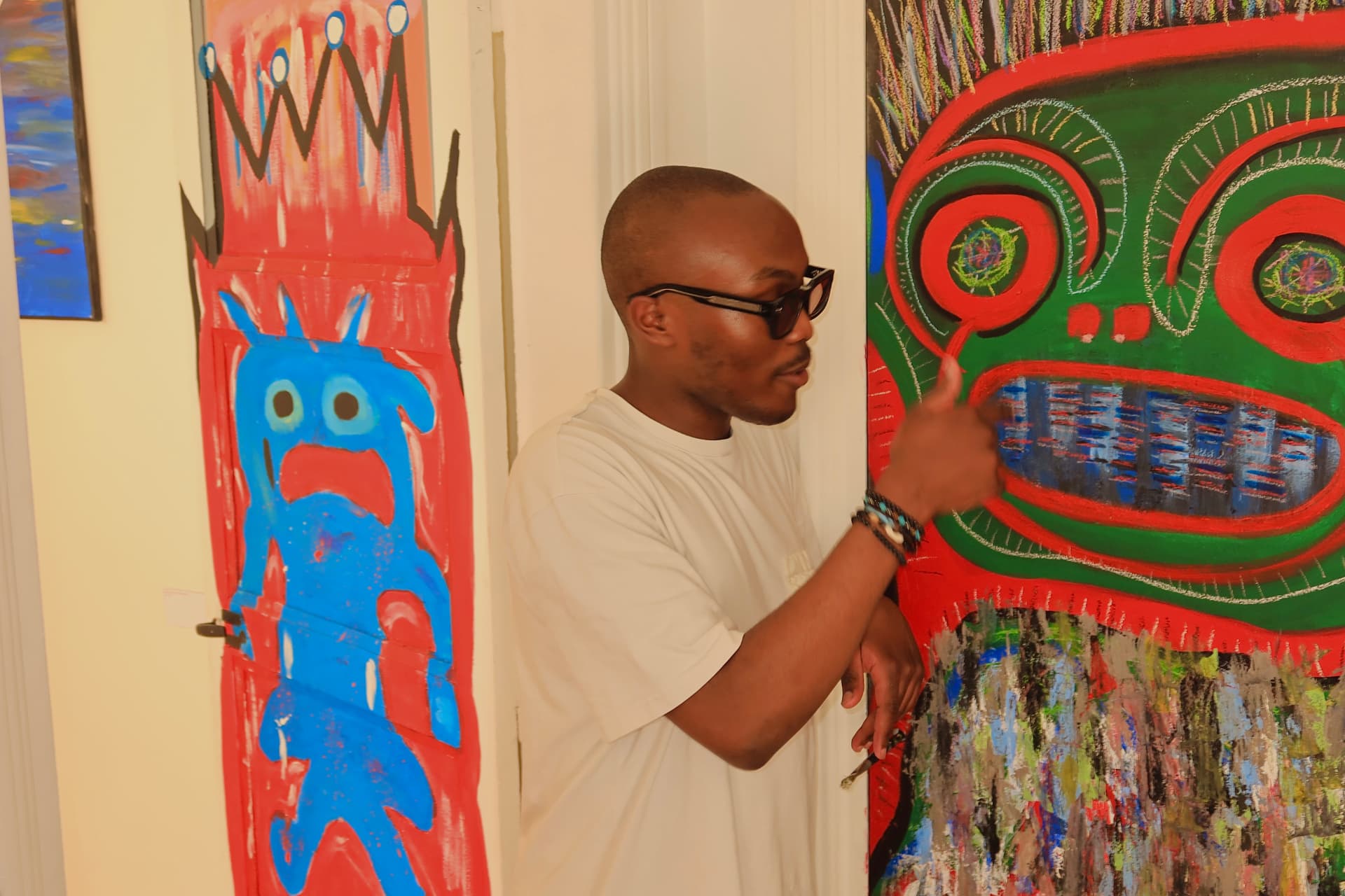 Kenth TCHEUFFA, alias Celeste To Close, devant ses peintures
